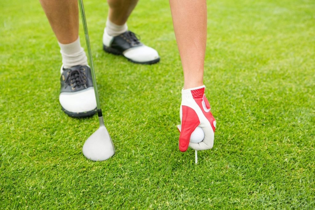 Golfer placing golf ball on tee at the golf course