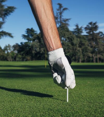 Golfer puts the golf ball on a tee